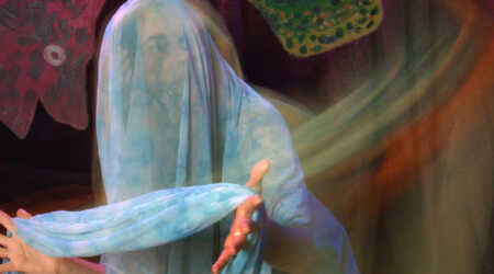 Veiled in sheer, blue fabric, actress Katherine Lyons peers cautiously in the distance.