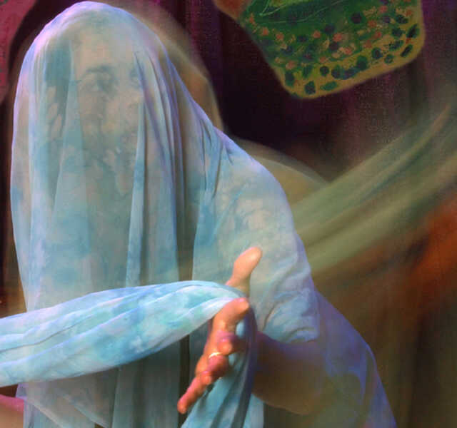Veiled in sheer, blue fabric, actress Katherine Lyons peers cautiously in the distance.