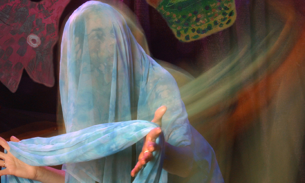 Veiled in sheer, blue fabric, actress Katherine Lyons peers cautiously in the distance.