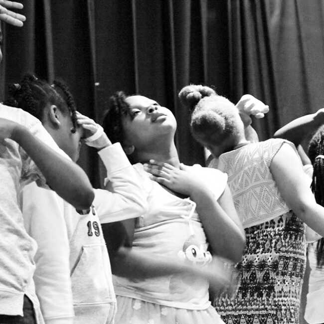 Children on stage in a row striking a very dramatic pose