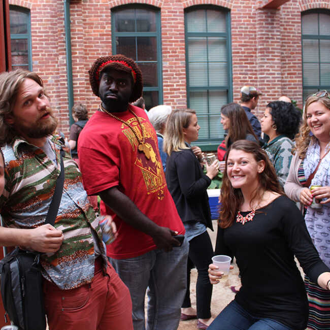 Artists and Staff tasing for a group photo in the courtyard of a renovated industrial building