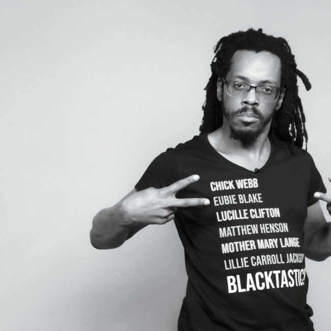 Black and white photograph of Baba Bomani in Blacktastic t-shirt.