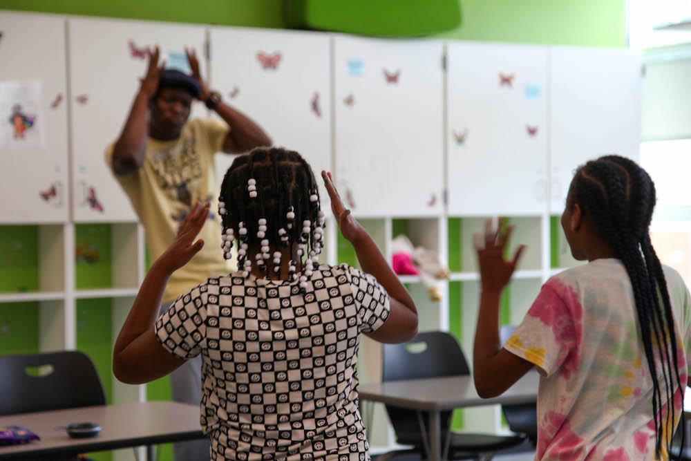 Students mimic movements of teaching artist standing at the back of the classroom.