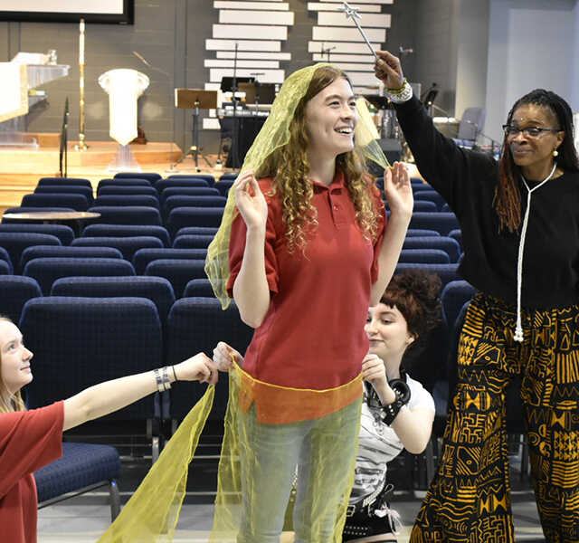 Tracie Jiggetts and students hold scarves and post mid-workshop.