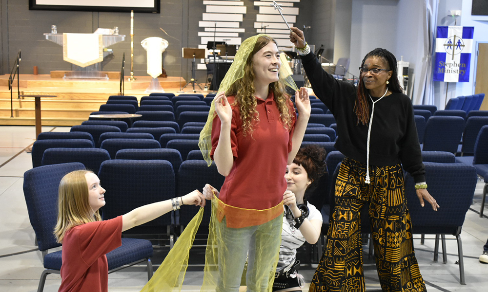 Tracie Jiggetts and students hold scarves and post mid-workshop.