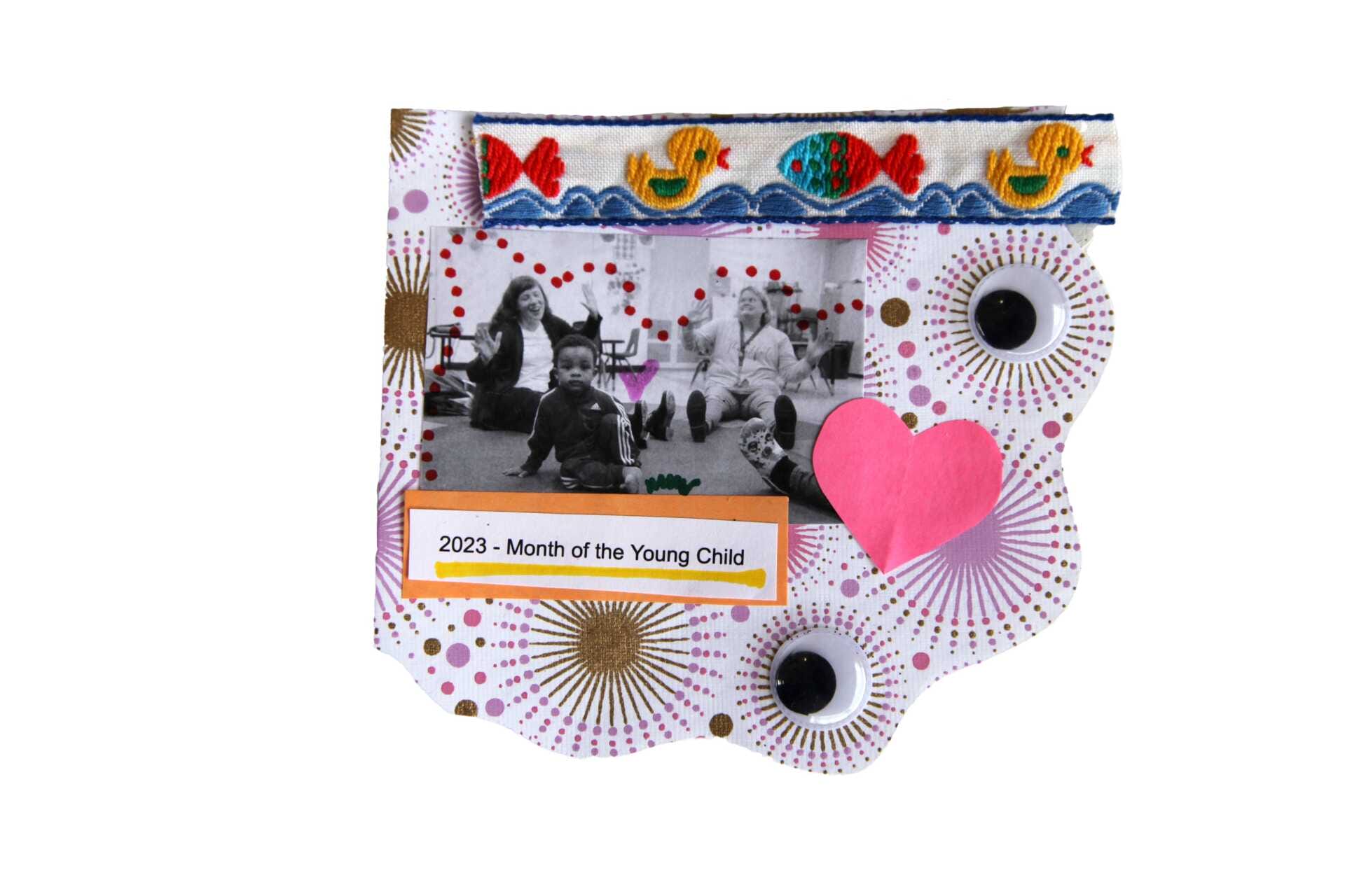 A vintage ribbon embroidered with playful fish in primary colors tops this collage celebrating Month of the Young Child. Teaching artist Marsha Searle sits on the floor with an early educator and young students as sunbursts, googly eyes, and a bright pink heart frame the image.