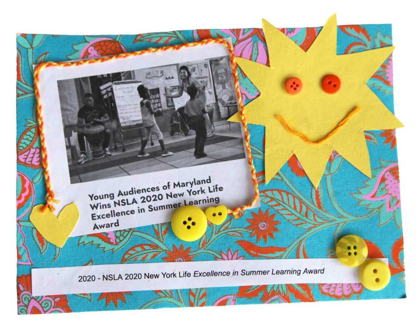 A smiling yellow sun-star beams in the corner over yellow buttons and hearts floating in a turquoise sky. An image of a teaching artist at the head of a classroom with the title,"Young Audiences of Maryland wins NSLA 2020 New York Life Excellence in Summer Learning Award."