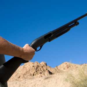 Man practice shooting mossberg shotgun in desert