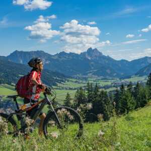 Woman on electric mountain bike on trail with mountain in the background