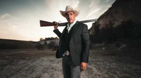 man dressed like cowboy with shotgun on his shoulder