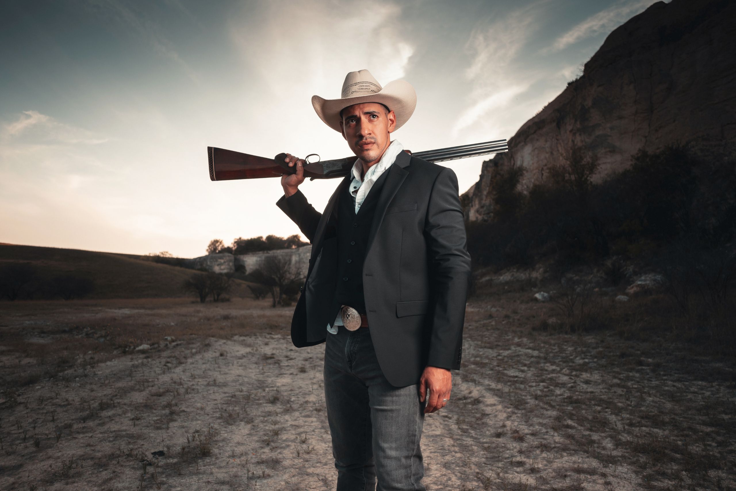 man dressed like cowboy with shotgun on his shoulder
