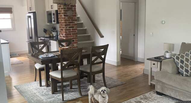 A toy dog standing in the middle of a kitchen with a custom stained maple wood floor.