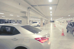 PRO MAGNO Centro de Eventos. Parte do estacionamento e parte de um carro prata no lado esquerdo