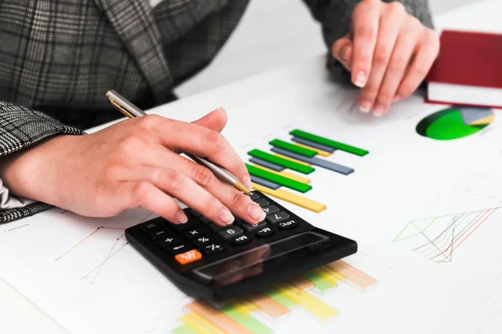 Person calculating cabin rental pricing with charts and graphs