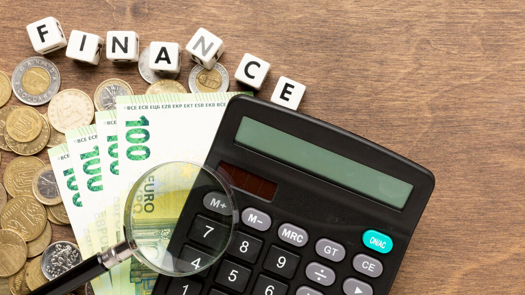 Money and a calculator under a magnifying glass, representing financial management for a trailer business.