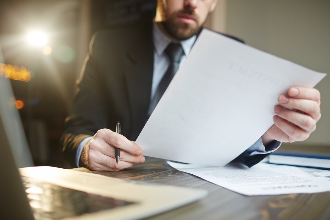 Individual holding a pen and reviewing a contract for a trailer rental business.