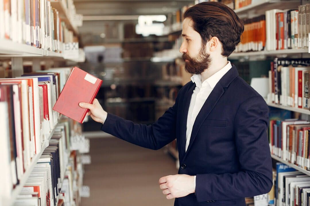 A person in an academic setting selecting a book representing textbook rental business