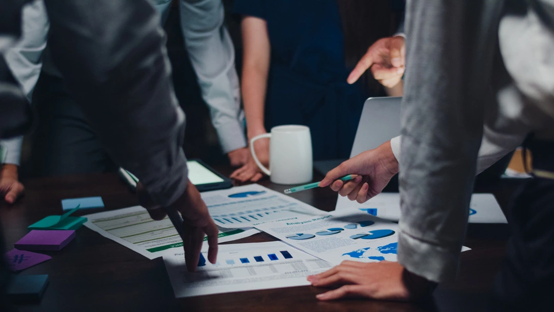People collaborating over a table with charts, representing car rental business planning
