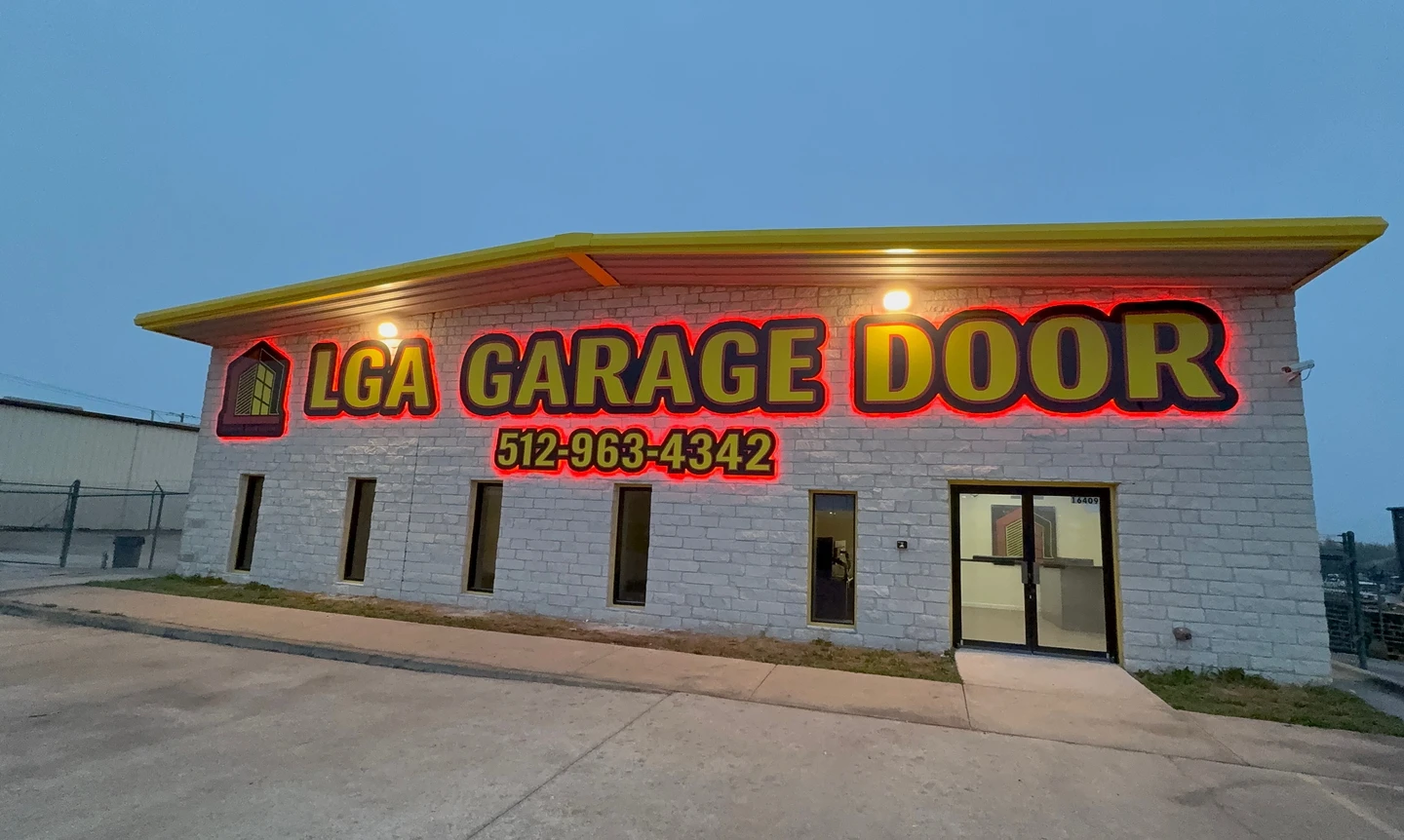 LGA Garage Door storefront in Austin, Texas, with bright neon signage on a modern stone building facade