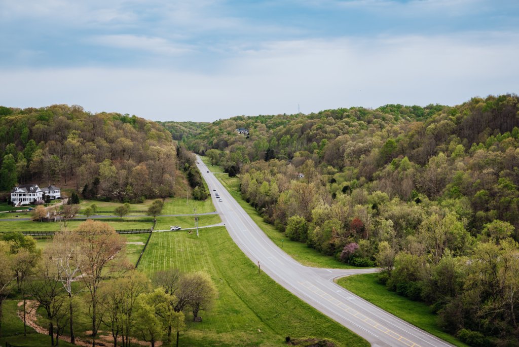 A winding road cuts through lush green hills dotted with trees and a few scattered houses in Williamson County, Tennessee.