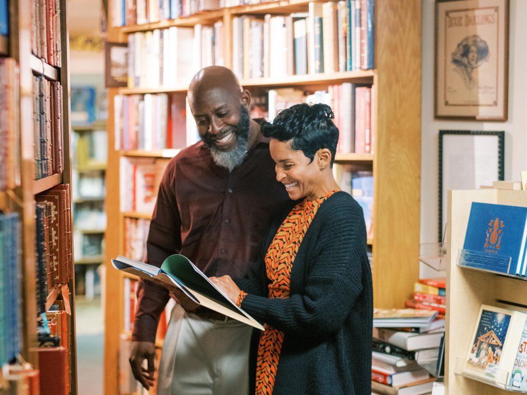 A man and woman are browsing books in a cozy bookstore, smiling as they examine a book together in Williamson County, Tennessee.