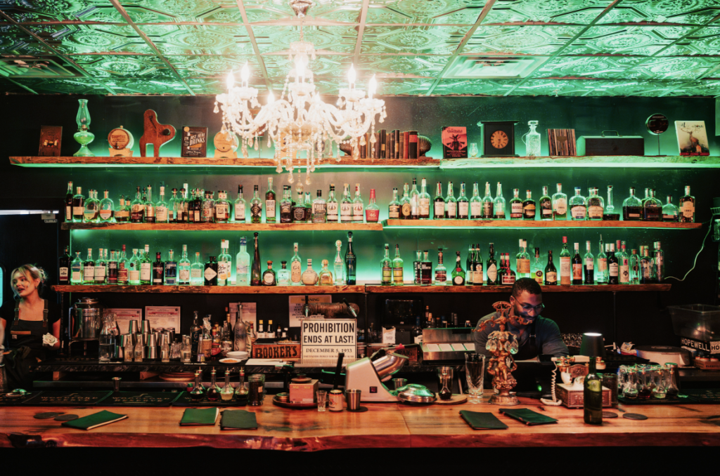 9 Unexpected Things To Do in Franklin A dimly lit bar with a chandelier, shelves of colorful bottles, and two bartenders in Williamson County, Tennessee.