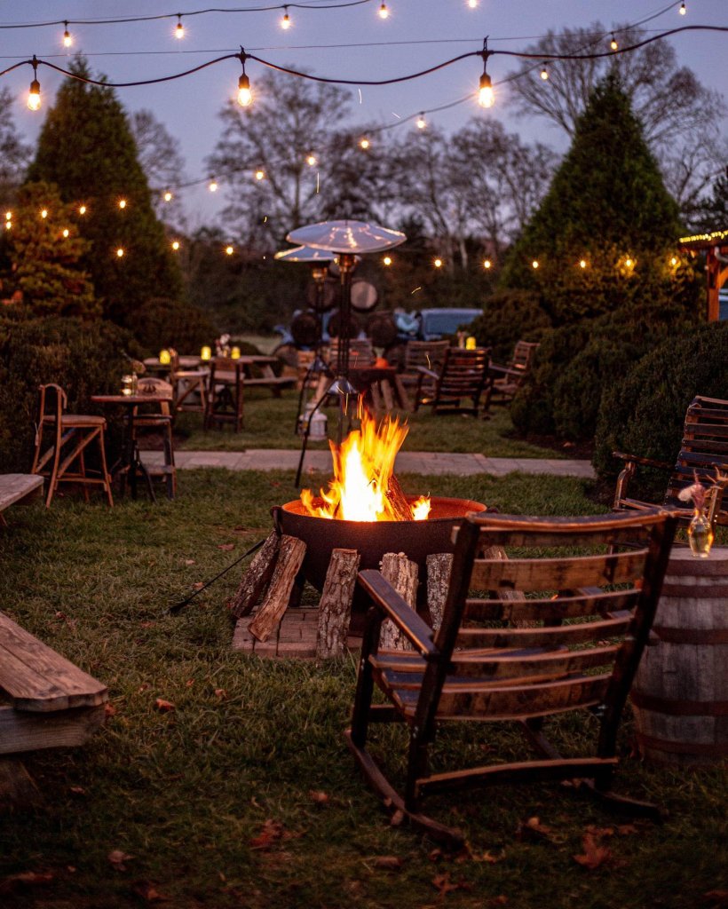 A cozy outdoor fire pit area with wooden chairs, string lights, and a warm fire in Williamson County, Tennessee.