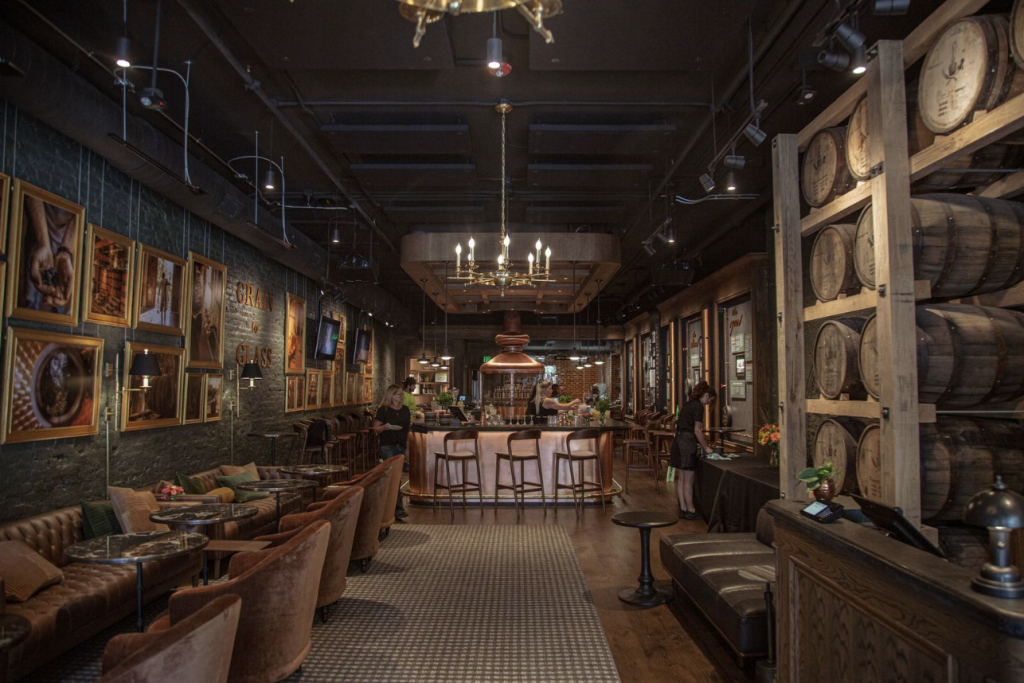 A dimly lit, upscale bar with wooden barrels, leather seating, and framed pictures on the walls in Williamson County, Tennessee.