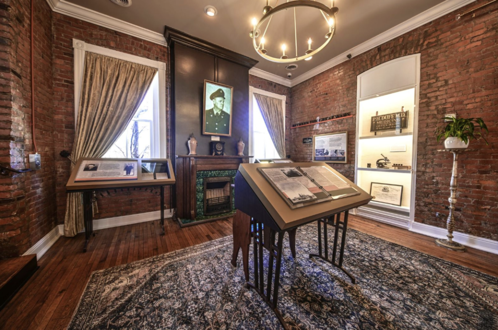 A museum room with brick walls, a chandelier, and historical exhibits including a portrait and a fireplace in Williamson County, Tennessee.