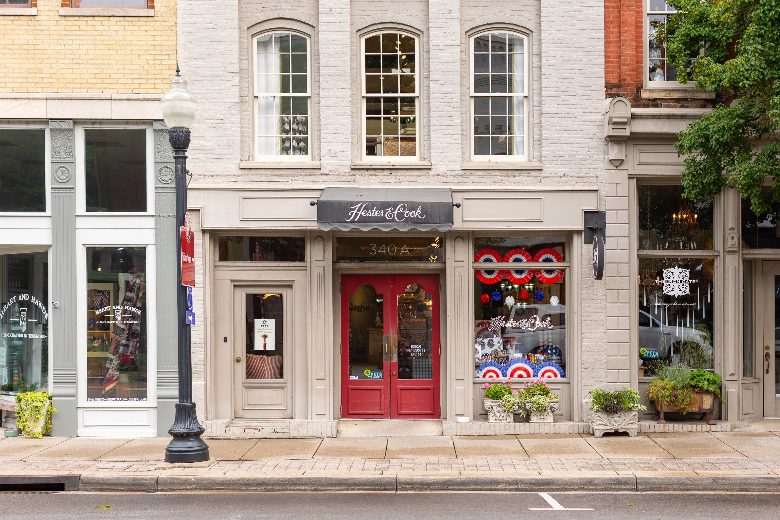 Hester & Cook A charming storefront with red doors and patriotic decorations on a quaint street in Williamson County, Tennessee.