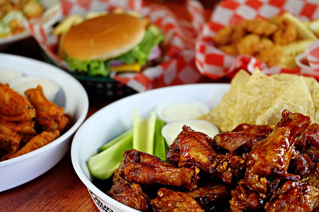 Assorted fried foods including chicken wings, burgers, fries, and onion rings on checkered paper in Williamson County, Tennessee.