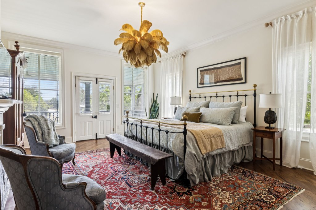 A luxurious bedroom with a large bed, ornate chandelier, and elegant furniture set on a vibrant oriental rug in Williamson County, Tennessee.