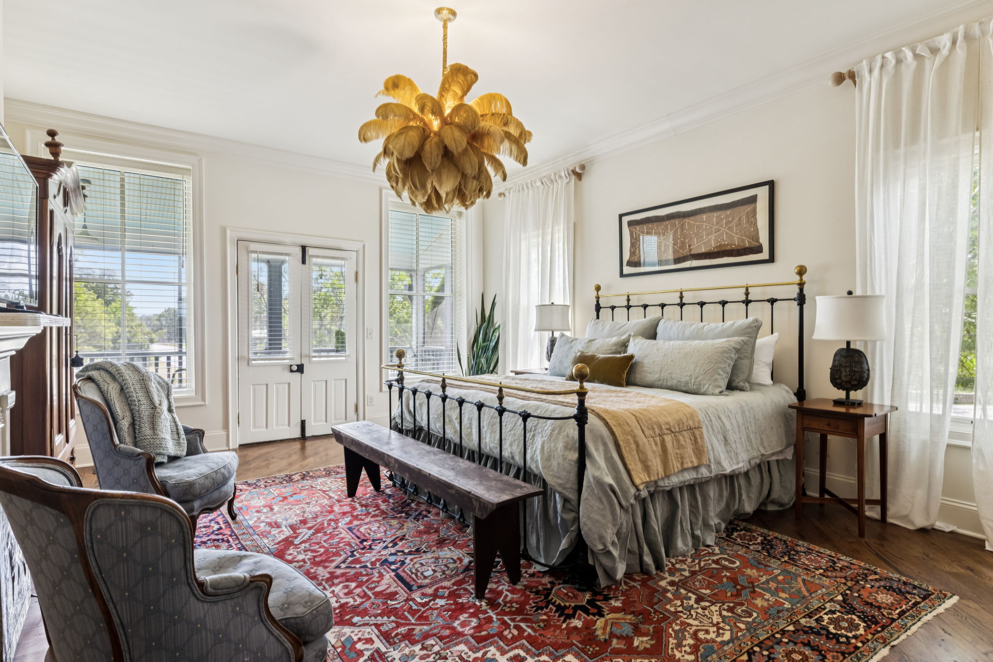 A luxurious bedroom with a large bed, ornate chandelier, and elegant furniture set on a vibrant oriental rug in Williamson County, Tennessee.