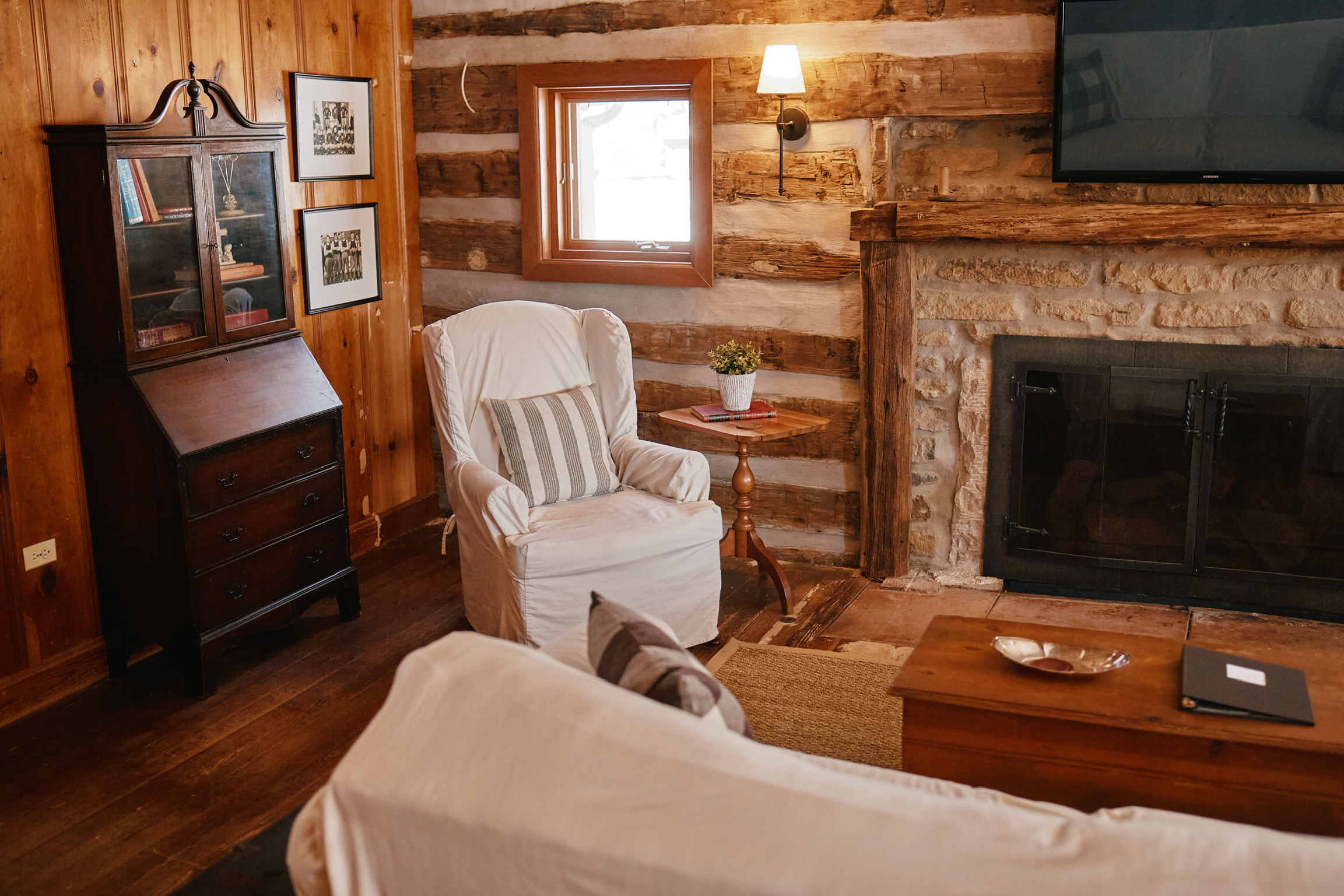 Arrington Rustic living room with log walls, stone fireplace, white furniture, and wooden accents in Williamson County, Tennessee.