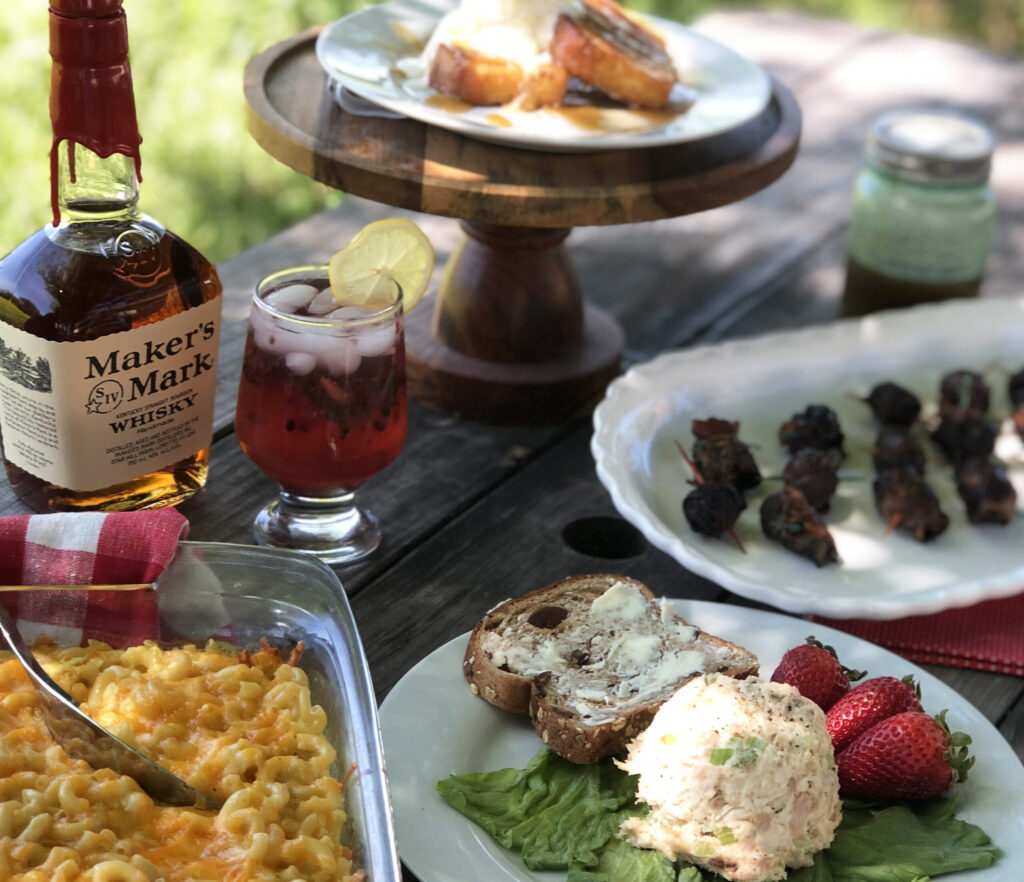 A rustic outdoor table set with a variety of Southern comfort foods and drinks in Williamson County, Tennessee.