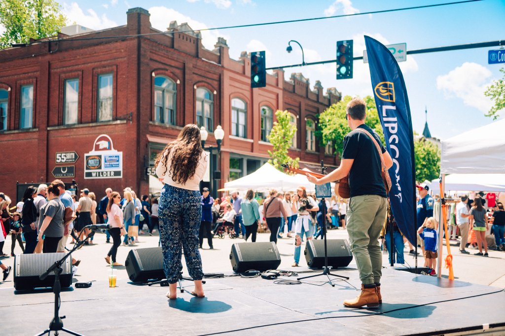A lively outdoor concert in a town square with a crowd enjoying a musical performance by a duo on stage in Williamson County, Tennessee.