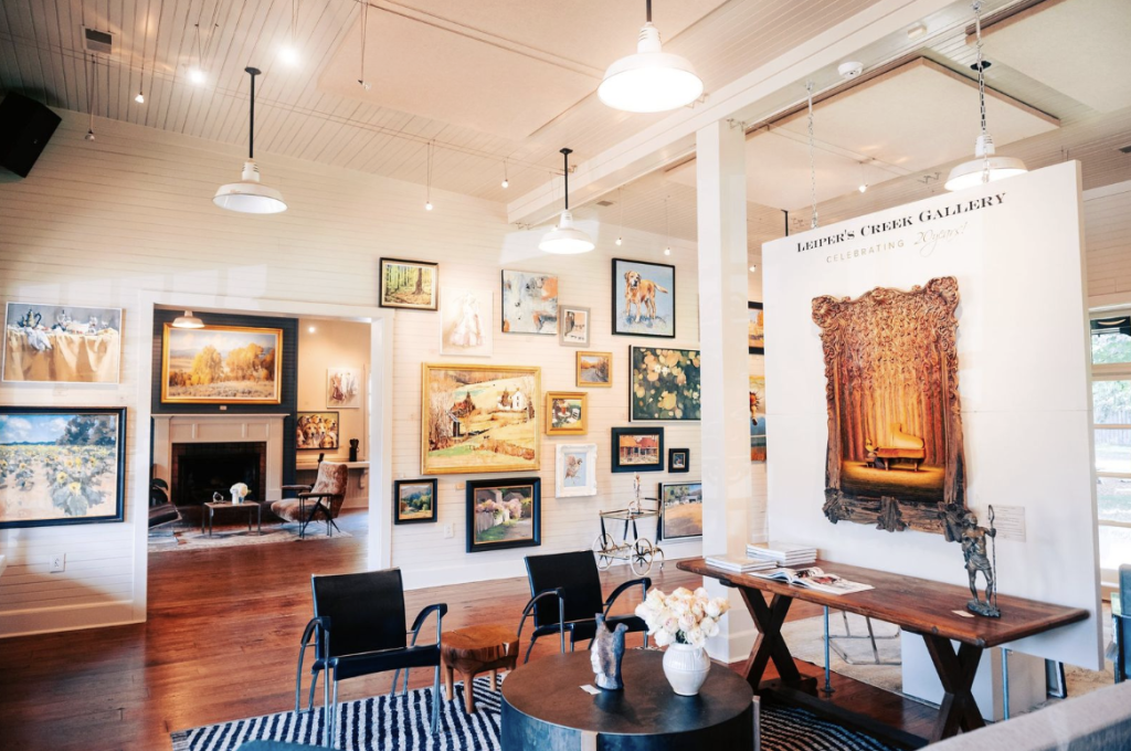 Art gallery with wooden floors, black chairs, and framed paintings on white walls in Williamson County, Tennessee.