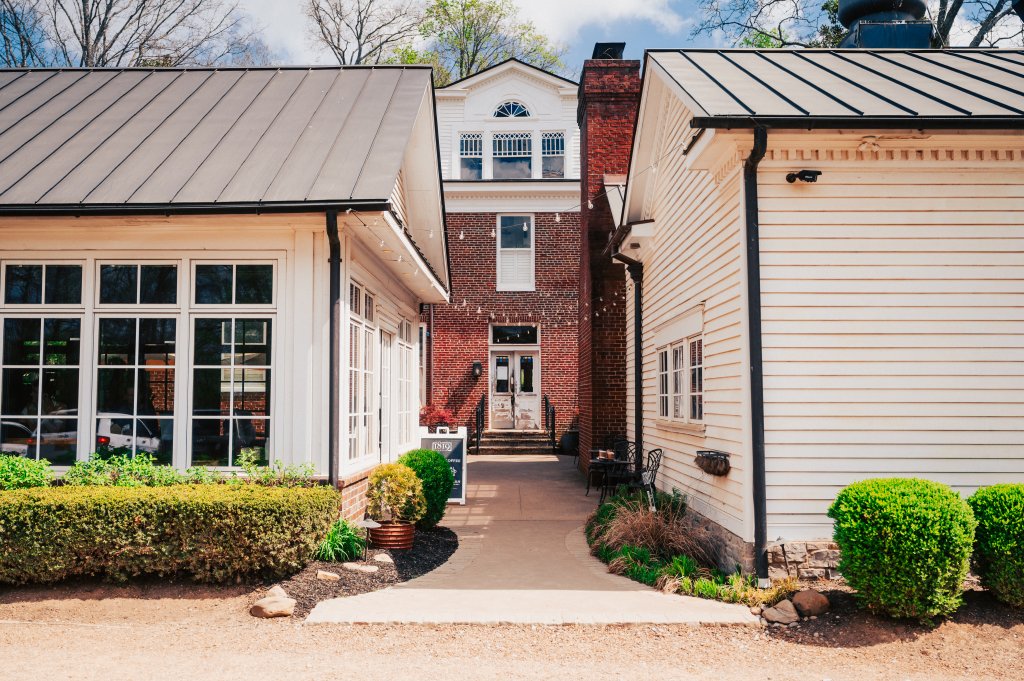 A charming courtyard is framed by two buildings with contrasting architectural styles: one with a red brick facade and the other with white siding and black trim in Williamson County, Tennessee.