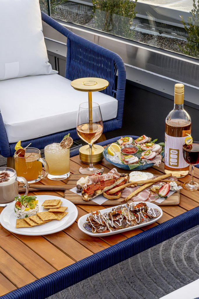 A luxurious outdoor dining setup with a variety of gourmet appetizers, cocktails, and wine on a wooden table in Williamson County, Tennessee.