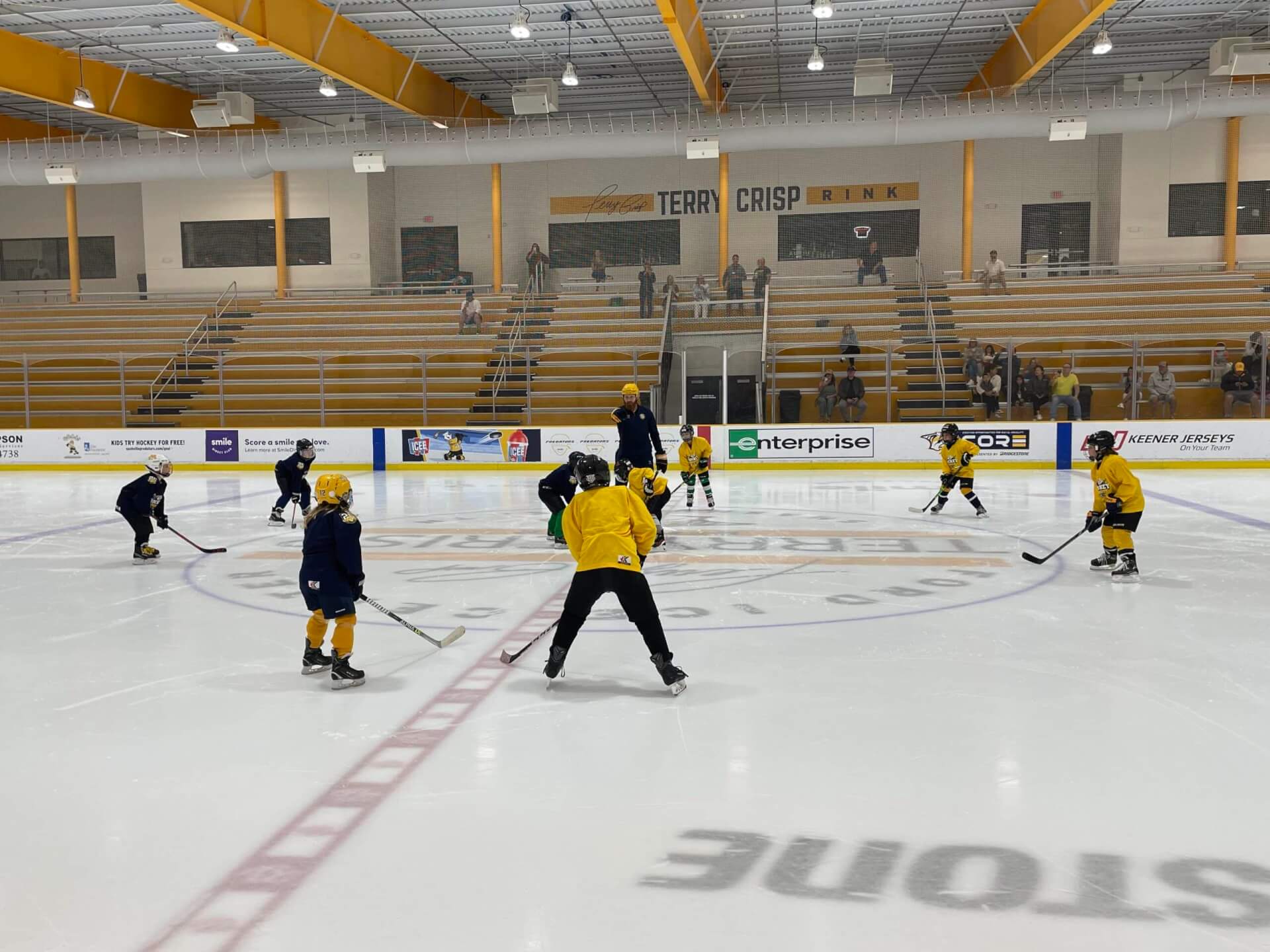 Youth ice hockey players in yellow and black uniforms skate on an indoor rink in Williamson County, Tennessee.