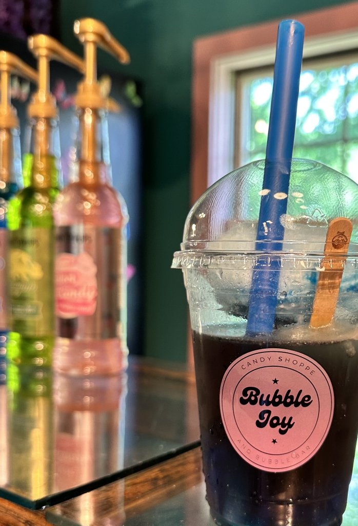 A colorful bubble tea shop with a variety of syrups and a refreshing bubble tea drink with a wooden spoon and blue straw in Williamson County, Tennessee.