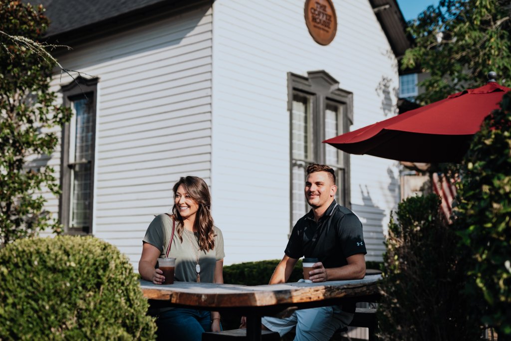 6 of Franklin's Best Coffees & Cocktails to Drink in the Fall Season A smiling couple sits at an outdoor table with coffee in front of a building in Williamson County, Tennessee.