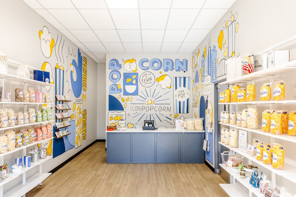 A brightly colored popcorn shop with shelves of popcorn and a mural on the wall in Williamson County, Tennessee.