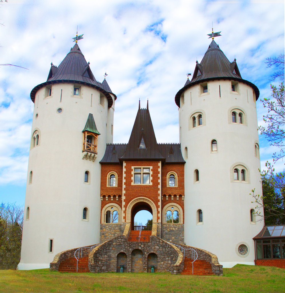 A majestic castle with twin white towers and a central red brick structure, set against a backdrop of a clear blue sky with scattered clouds in Williamson County, Tennessee.