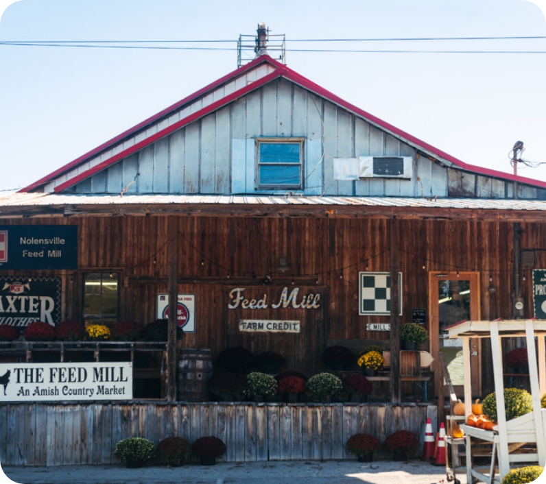 A rustic wooden feed mill with a red roof and a sign reading 'Feed Mill' and 'Farm Credit' in Williamson County, Tennessee.