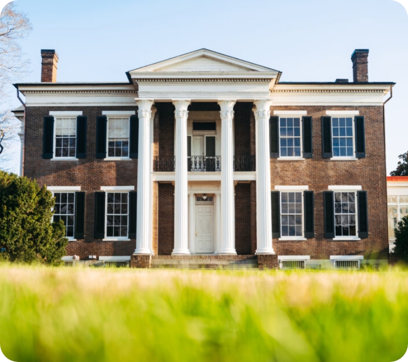 A stately brick mansion with white columns and shutters stands amidst a lush green lawn in Williamson County, Tennessee.