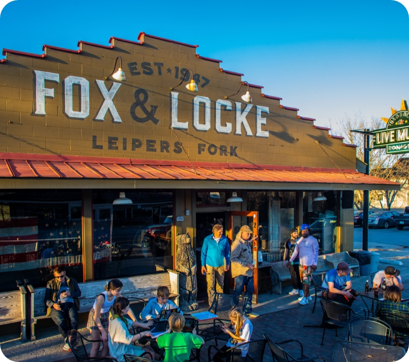 A group of people enjoy a sunny day outside a historic restaurant with a red roof in Williamson County, Tennessee.