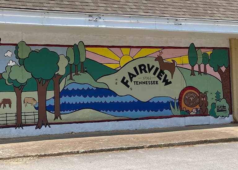 A colorful mural depicts a serene landscape with trees, animals, and a river in Williamson County, Tennessee.