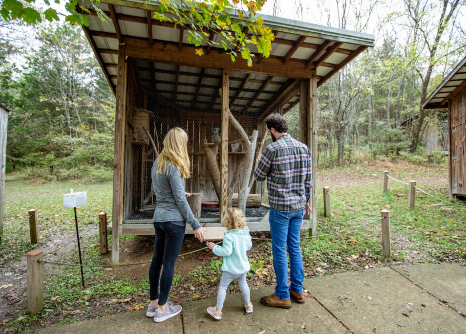 Brentwood A family of three stands outside a wooden animal enclosure in a forest setting in Williamson County, Tennessee.