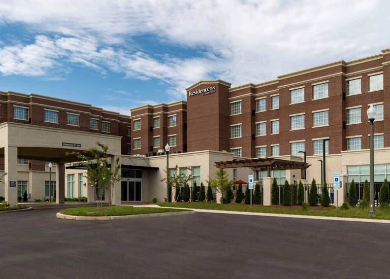 A modern hotel with a brick facade and covered entrance, surrounded by landscaped grounds in Williamson County, Tennessee.